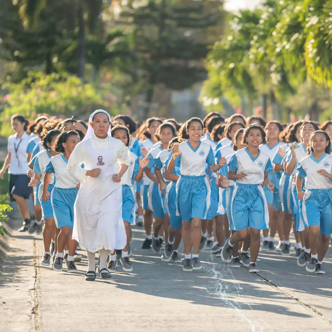 A Sister of Mary running with girls in the Philippines