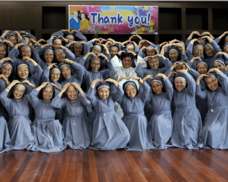 A group of Sisters of Mary in Korea with a Thank You banner behind them.
