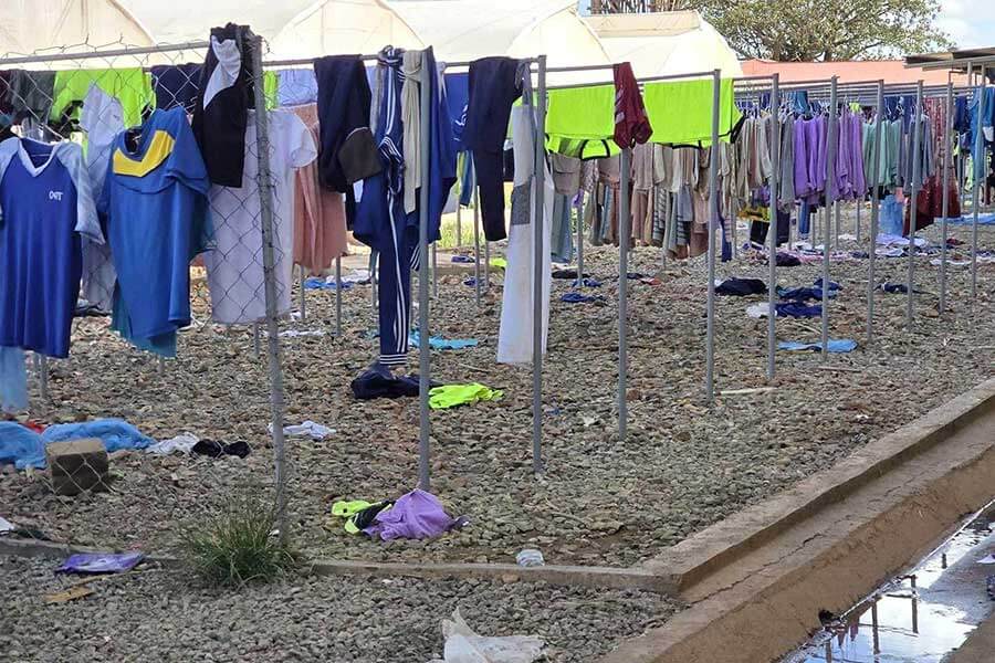 Outdoor laundry area at Dodoma Boystown with clothes hanging on lines and some clothes scattered on the ground below.