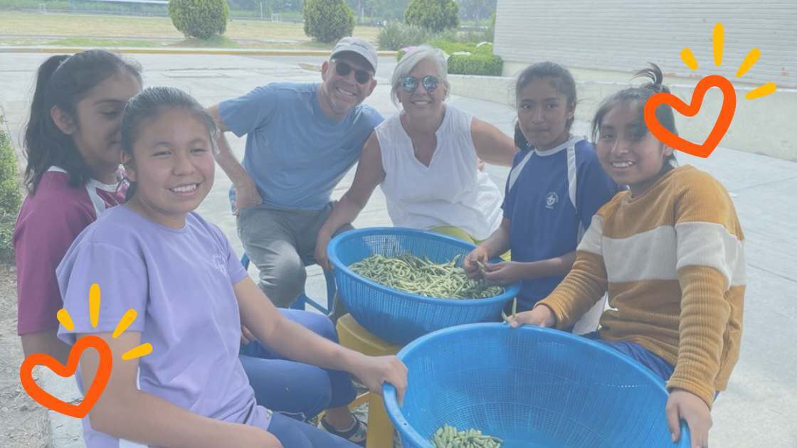 Volunteers spend time with children served by World Villages for Children while sorting vegetables outdoors.