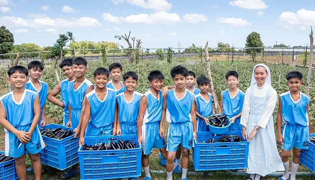Sisters-of-Mary-World-Villages-for-Children-Boystown-Adlas-Philippines Students from Boystown Adlas in the Philippines harvest eggplants with a Sister of Mary in the school garden.
